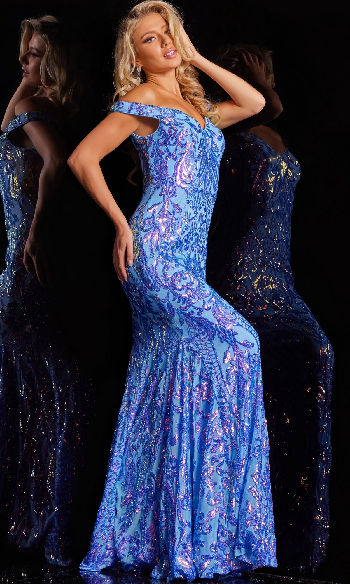 A woman poses in the Jovani Long Sweetheart Sequin-Print Prom Dress 23675—a shimmering blue, form-fitting gown—her hand in her hair, reflected against a dark background.